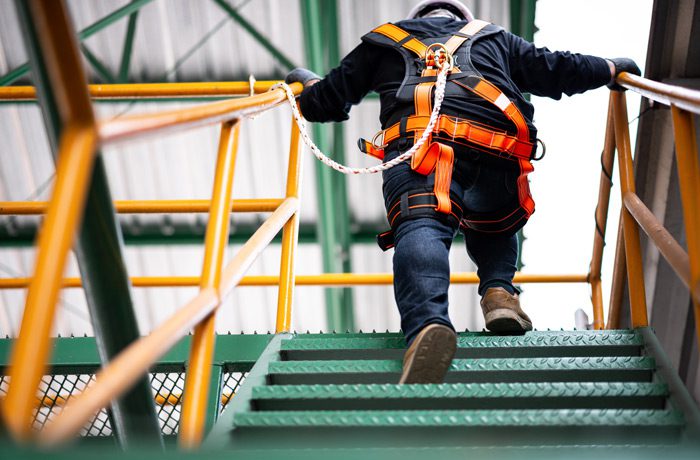Construction-worker-wearing-safety-harness-while-climbing-stairs