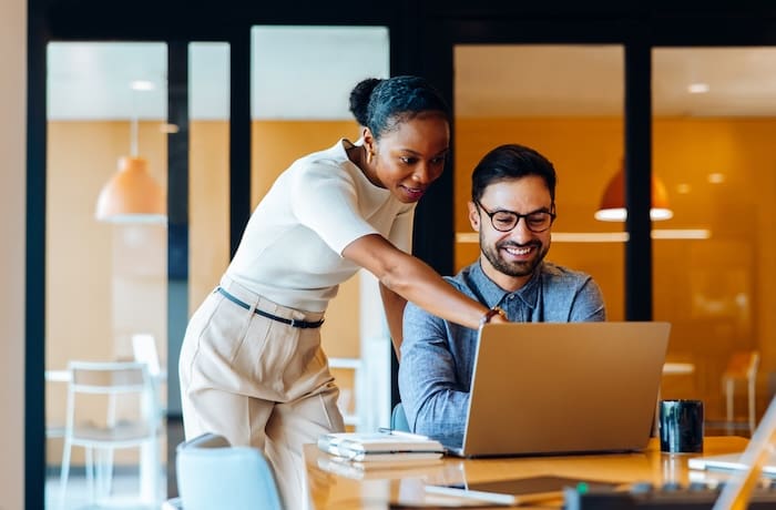 business professionals discussing a project while using a laptop