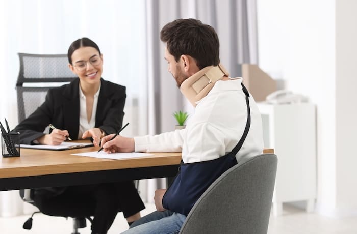 injured man signing document in lawyer's office