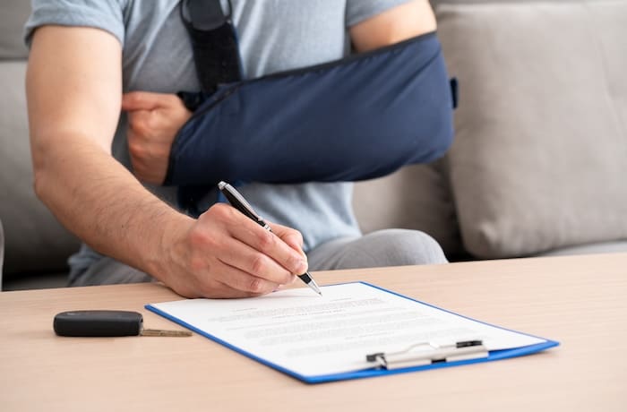 man with broken arm in sling signing a document
