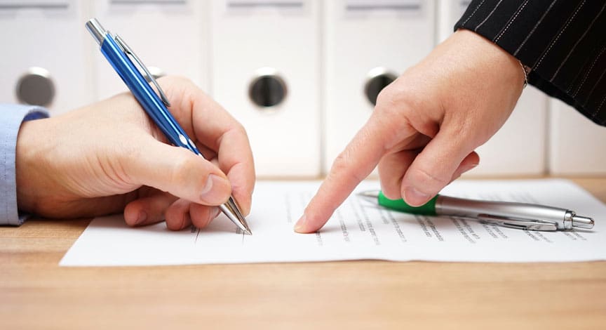 attorney-pointing-to-a-signature-line-while-a-client-signs-a-document