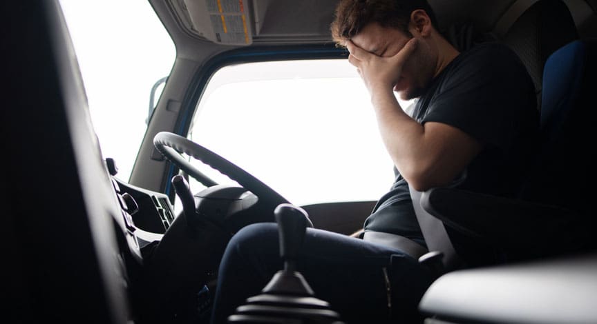 truck-driver-sitting-in-the-cab-with-his-head-in-his-hands