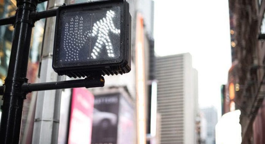 Crosswalk-sign-in-a-busy-city