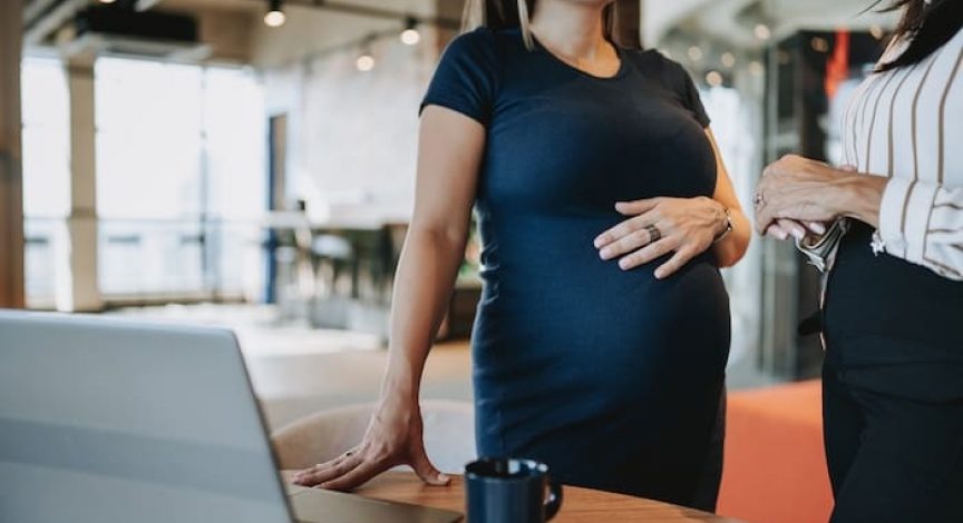 pregnant businesswoman talking to coworker